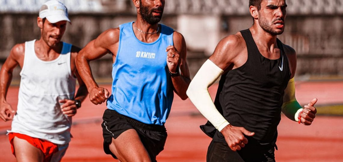 Three male athletes intensely focused on a track, captured mid-race showcasing their dedication.