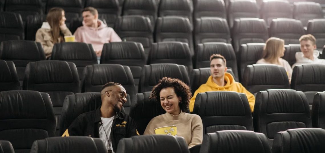 Young adults having fun in an empty movie theater with popcorn.